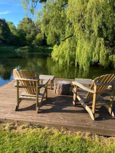 GlasburyCwmbach Lodge luxury B&B的两个木凳坐在湖边的码头上