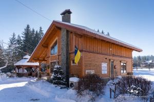 沃罗赫塔Girska Hatyna Vorohta的雪上挂着旗帜的小木屋