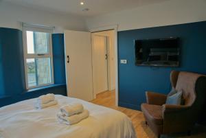 安纳隆Irish Sea Cottage的一间卧室设有蓝色的墙壁和一张带毛巾的床。