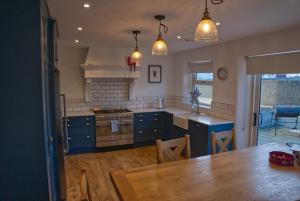安纳隆Irish Sea Cottage的厨房配有蓝色橱柜和木桌
