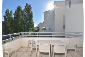 勒格罗-迪鲁瓦T2 Résidence Cap Camargue avec piscine的大楼阳台上的白色桌椅