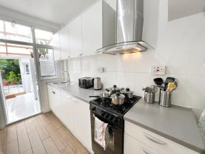 伦敦Luxurious House near Excel- Air Conditioning, 9 Beds, 2 Baths, Garden, fast WiFi的一间带炉灶的厨房 窗边的顶部烤箱