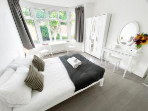 伦敦Luxurious House near Excel- Air Conditioning, 9 Beds, 2 Baths, Garden, fast WiFi的白色卧室配有一张大床和一张书桌