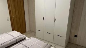 OmmersheimFerienwohnung Kessler的一间设有白色橱柜和一张床的房间