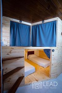 萨尔塔LEAD Pods Hostel的小屋设有两张双层床和蓝色窗帘