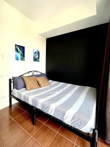 马尼拉Mey’s Condo in Pasig - 1BR with Balcony的卧室内的一张床位,卧室内有黑色的墙壁