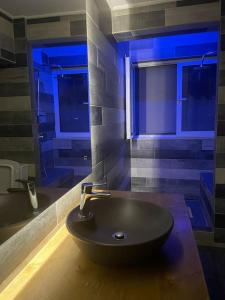 米蒂利尼The Beehive的浴室设有黑色水槽和蓝色的灯光