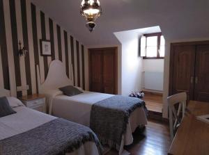 Villanueva de OscosHOTEL RURAL OSCOS的酒店客房设有两张床和一张桌子。