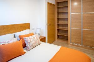 布埃乌Apartamento Solpor Bueu的一间卧室配有一张带橙色枕头的床和一个衣柜。