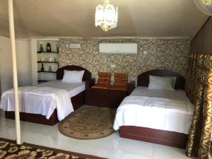 Al WāşilAl Khamail Land for Greenhostel的一间卧室配有两张床和吊灯。