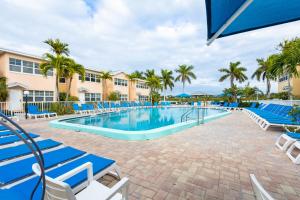 克利尔沃特Premier 2BD Waterfront Condo Barefoot Beach Resort的一个带蓝色椅子的游泳池,棕榈树