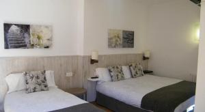 利亚沃尔西HOTEL LAMOGA的酒店客房设有两张床,墙上挂有绘画作品