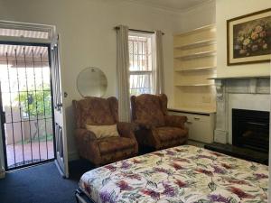 阿德莱德Carolyn's Cottage的一间卧室配有一张床、一把椅子和一个壁炉