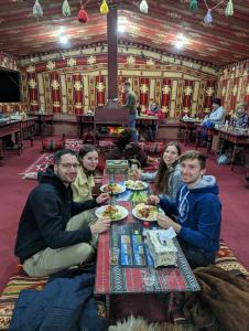 瓦迪拉姆Bedouin host camp& with tour的一群坐在餐桌上吃食物的人