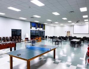 萨尼亚Residence & Conference Centre - Sarnia的配有乒乓球桌、桌子和椅子的房间