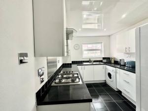 利物浦Liverpool Getaway Home!的厨房配有白色橱柜和炉灶烤箱。