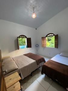 伦索伊斯Terra Hostel e Pousada的一间卧室设有两张床和两个窗户。