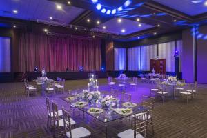 蓬塔卡纳Jewel Palm Beach的宴会厅配有桌椅和紫色照明