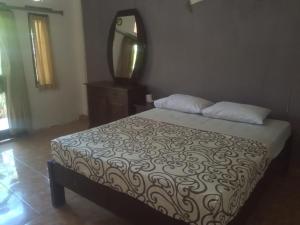 乌鲁瓦图毕龙博特家庭旅馆的卧室配有一张壁挂镜子的床