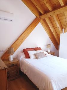 阿罗约弗里奥Duplex El Refugio de La Bolera的卧室设有白色的床和木制天花板。