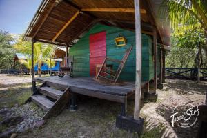 PetacaltepeTapas & Surf的一座色彩缤纷的小屋,门廊上摆放着两把椅子