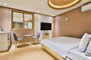 Yangsan时代酒店的卧室配有一张床和一张桌子及椅子