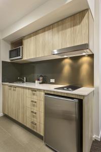 布里斯班奎斯特乌龙戈巴公寓的厨房配有木制橱柜和炉灶烤箱。
