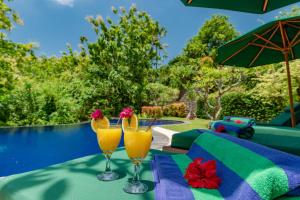 罗威那Alamanda Lovina Resort的游泳池畔桌子上放两杯橙汁