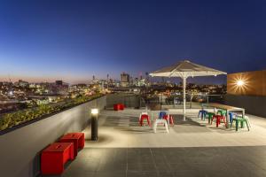 布里斯班奎斯特乌龙戈巴公寓的屋顶露台配有色彩缤纷的椅子和遮阳伞。