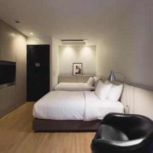 清迈The Sayla hotel(Baan Sayla)的一间卧室配有一张大床和一张黑椅