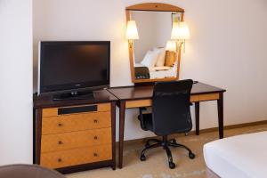富山富山皇冠假日酒店&度假村的一间卧室配有一张桌子、一台电视和一把椅子