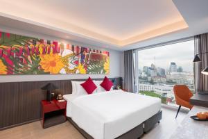 曼谷Maitria Hotel Rama 9 Bangkok - A Chatrium Collection的卧室设有白色的床和大窗户