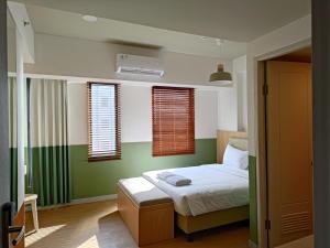 当格浪Hotel Osaka PIK2的一间卧室设有一张带绿色墙壁和窗户的床。