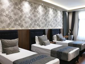 伊斯坦布尔GRAND ÜSKÜDAR OTEL的酒店客房带两张床和一面墙