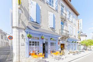 Arudy罗杰斯法国酒店的街道上一座配有黄色桌椅的建筑