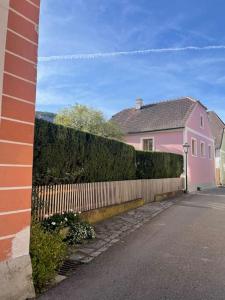 杜伦斯坦Altes Winzerhaus in der Wachau - neu renoviertes Haus mit Terrasse的一座粉红色的房子,房子旁边设有围栏