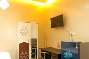 谏义里HP Residence Mitra RedDoorz near Alun Alun Kediri的客房设有书桌和墙上的电视。