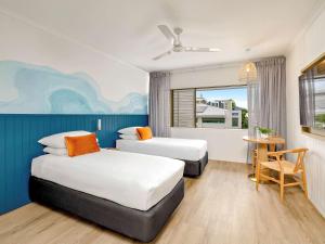 凯恩斯Mercure Cairns的酒店客房设有两张床和一张桌子。