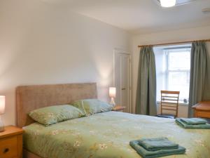 阿伯劳尔Rinnes Cottage的一间卧室配有一张带绿色床单的床和一扇窗户。