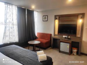 贾姆谢德布尔HOTEL K79的酒店客房带一张床、一台电视和一把椅子