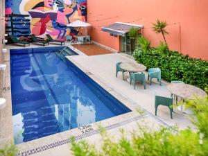 贝伦ibis Styles Belem Nazare的一座带桌椅的游泳池位于酒店大楼旁