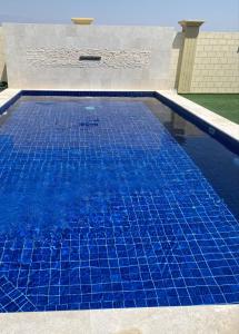 塞拉莱Alnoor Mirbat的游泳池的顶部铺有蓝色瓷砖