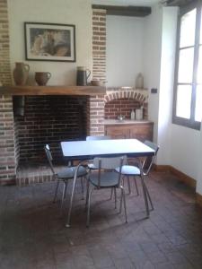 Gîte en pleine nature calme & tranquillité assurée的砖砌壁炉的客房内的桌椅