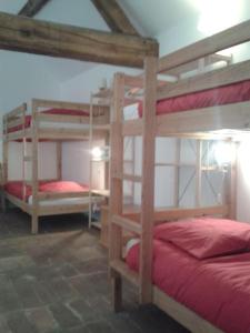 Gîte en pleine nature calme & tranquillité assurée的一间客房配有三张双层床和红色床单。