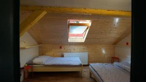 SloupChata pod hradem的阁楼卧室设有两张床和窗户。