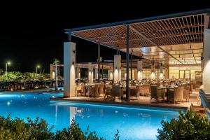 蒂加基阿斯蒂尔奥德修斯科斯度假村和Spa中心的游泳池,晚上有餐厅