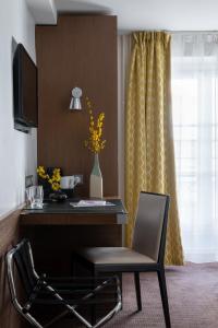 巴黎克里赛酒店的客房设有一张桌子、一把椅子和一台电视