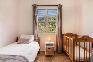 桑塔纳Casa da Olides - T3的一间卧室设有一张婴儿床和一扇窗户。