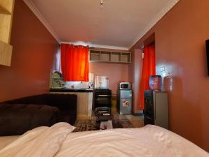 KikuyuPine Residency w Secure Parking, Wifi, Netflix & Rooftop Views的一间设有床铺的客房和一间带红色窗帘的厨房