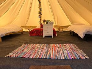 沃金厄姆Strawberry Fields Glamping at Cottrell Family Farm的帐篷配有两张床和地毯